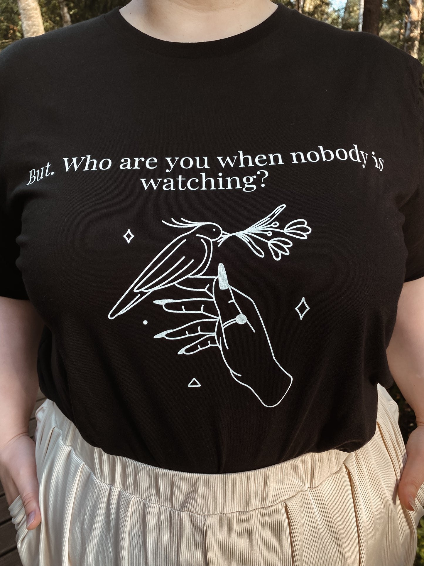 Person wearing a black t-shirt with white graphic and text outdoors